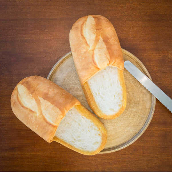 Chaussons baguette posés sur une planche à pain ronde, à côté d’un couteau à pain.