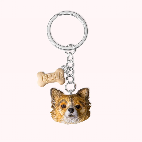 Portrait d’un chien accroché à l’anneau d’un porte-clefs, avec son nom personnalisé.