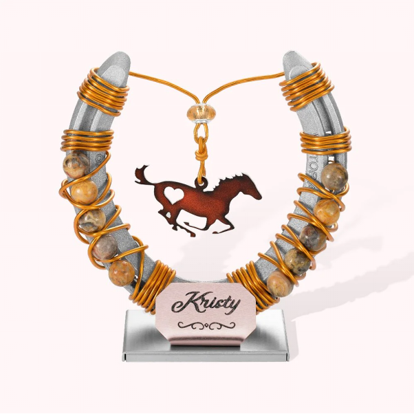 symbole commémoratif en forme de fer-à-cheval et présentant un cheval au galop tenu par des fils en acier doré. 